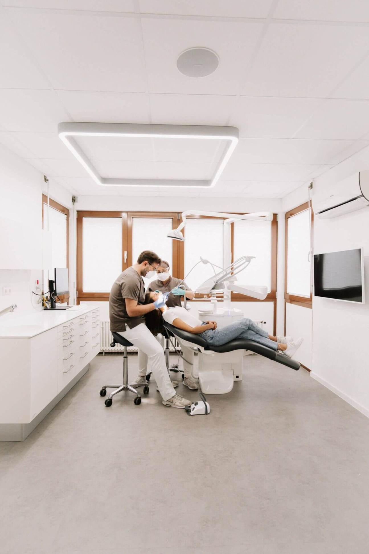 Behandlungszimmer mit Zahnarzt und Assistenz bei der Arbeit
