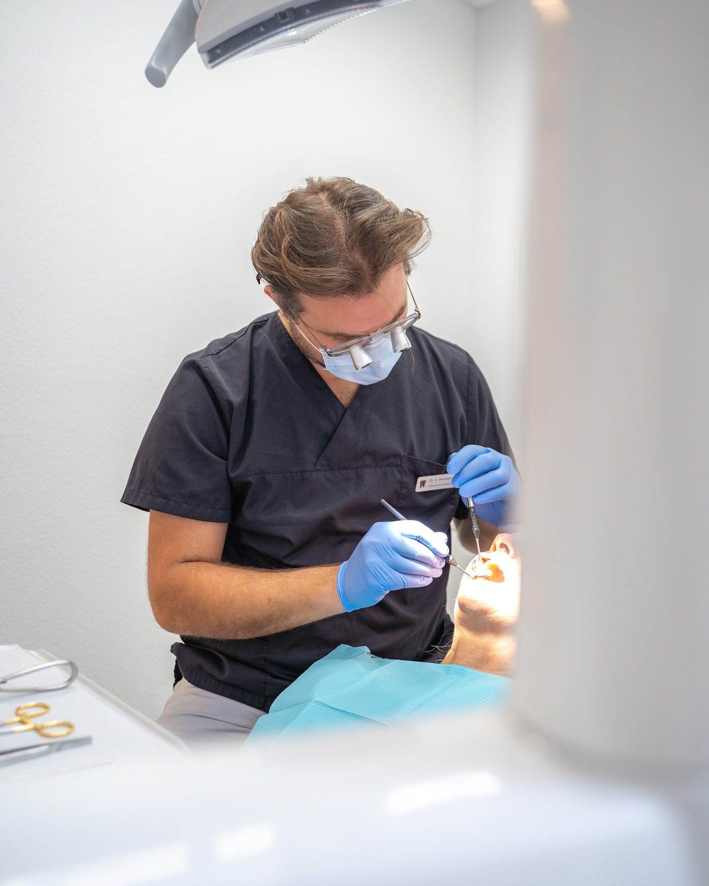 Zahnarzt mit Lupenbrille bei der Behandlung einer Patientin