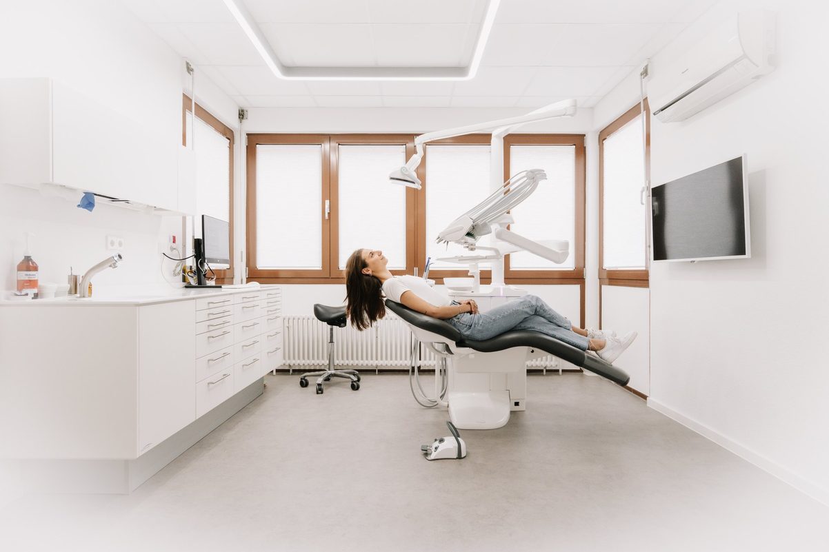 Helles Behandlungszimmer der Praxis mit Patientin auf dem Stuhl