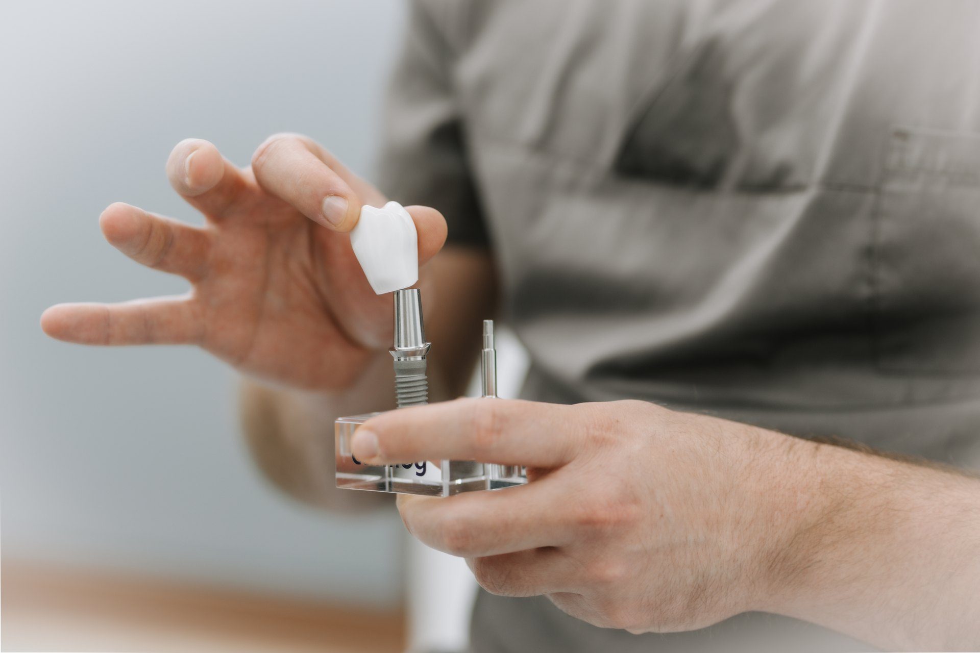 Hand hält ein Implantat-Modell mit Krone