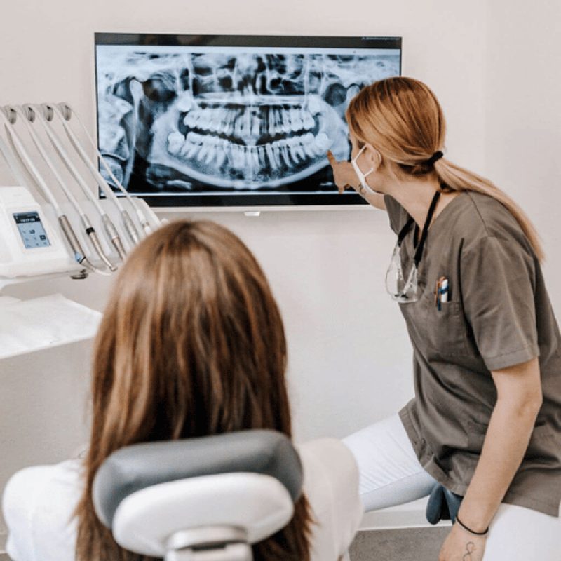 Zahnärztin erklärt einer Patientin das Röntgenbild am Bildschirm