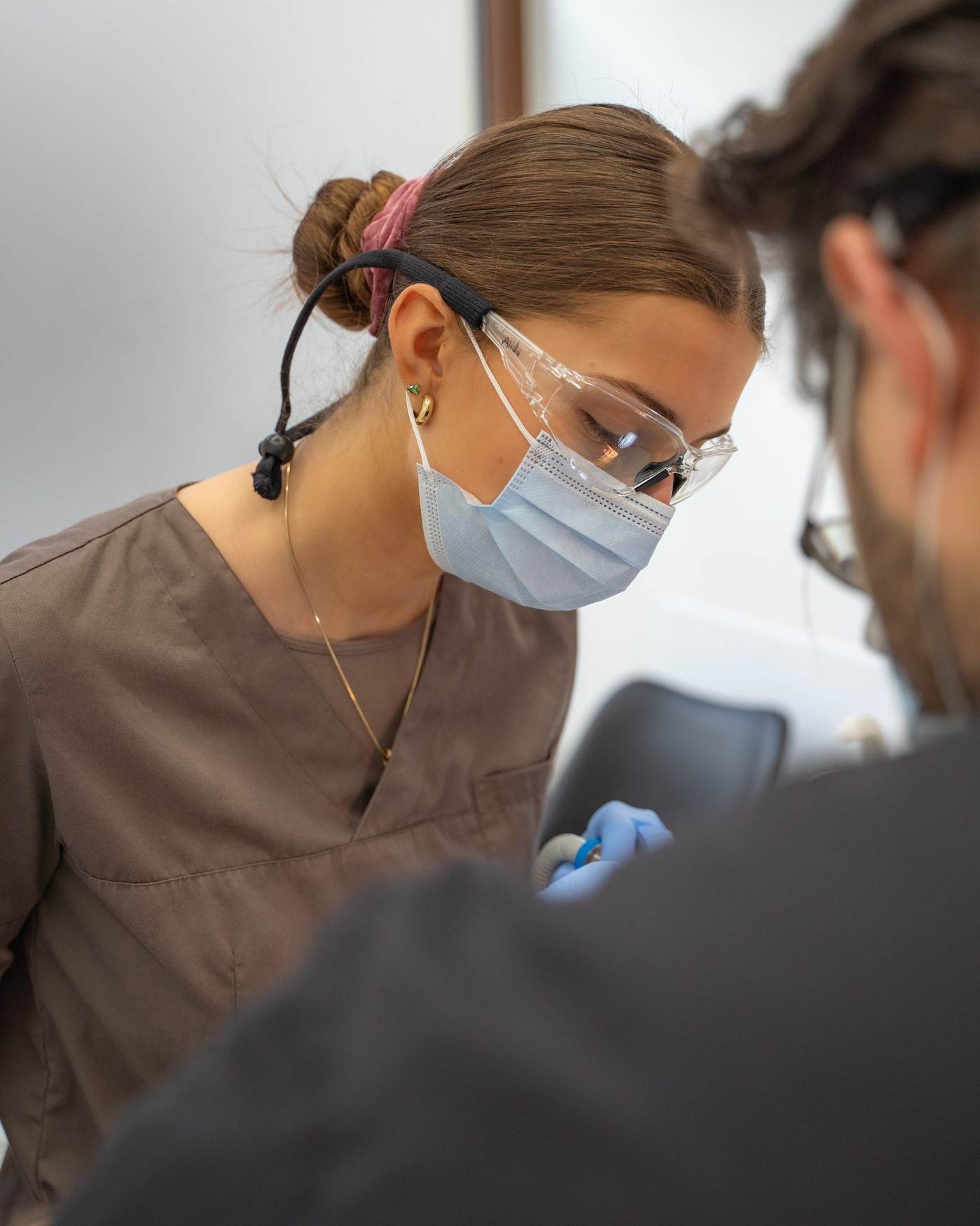 ZFA mit Schutzbrille und Mundschutz bei der Behandlungsassistenz